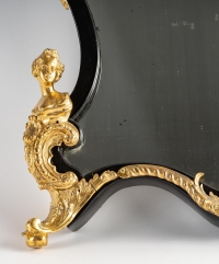 Un miroir mural ou à poser de style Napoléon III en bronze doré et bois noirci.