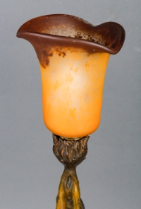Lampe en bronze patiné représentant une femme retenant une tulipe en pâte de verre.  Époque Art Nouveau vers 1900.  Signée Firmin Bate