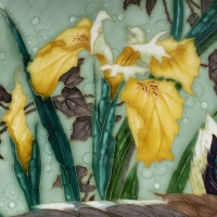 Plat en céramique émaillée à décor polychrome représentant un canard colvert en plein vol au dessus d’un étang, entouré de fleurs