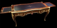 Bureau plat de style Louis XV en placage de bois de rose et bois de violette, ouvrant par trois tiroirs en ceinture et reposant sur des pieds cambrés.