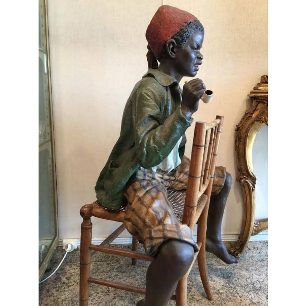 Enfant noir en terre cuite sur une chaise en bambou et cannage. Réf: 356 | Biron Enfant noir en terre cuite sur une chaise en bambou et cannage. Réf: 356