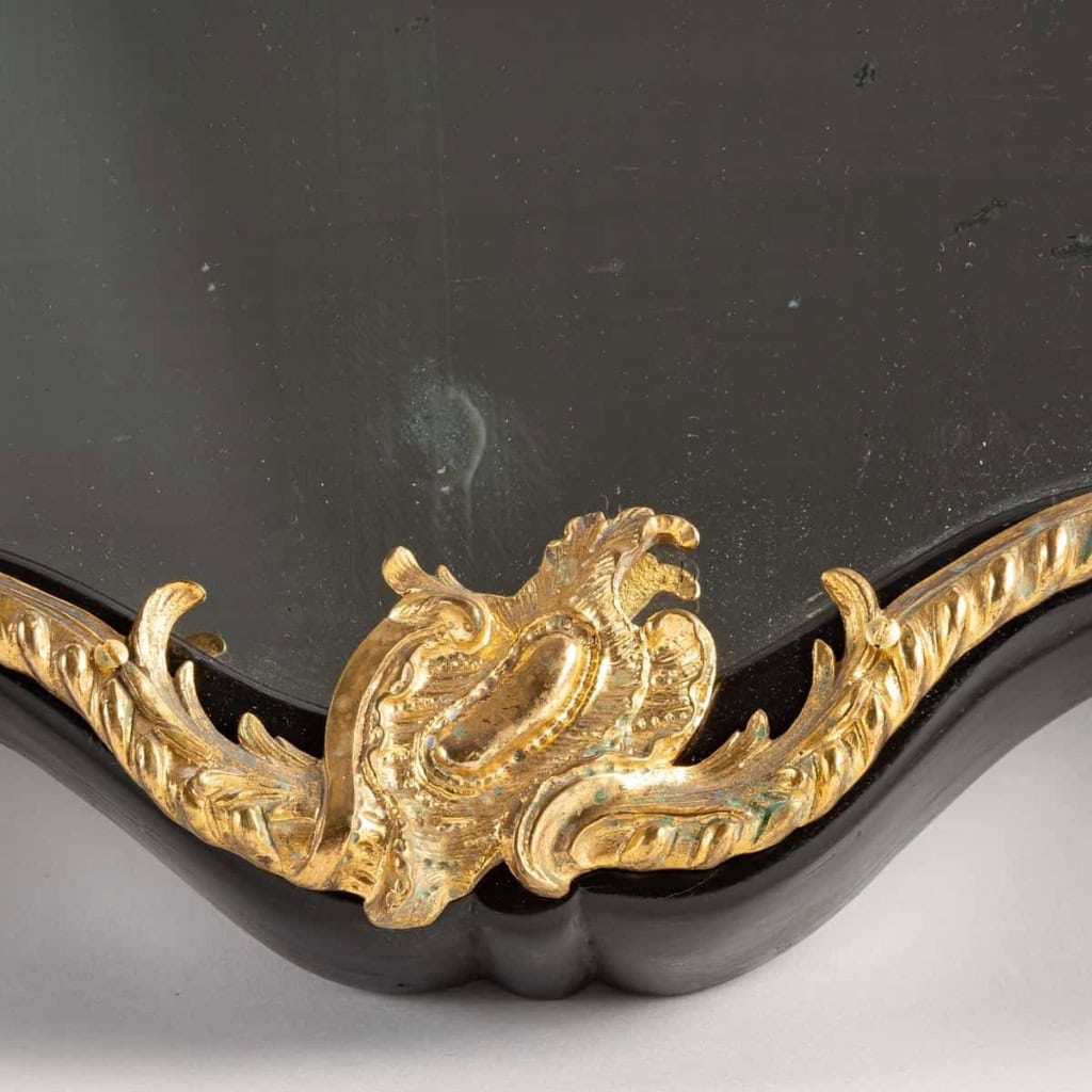 Un miroir mural ou à poser de style Napoléon III en bronze doré et bois noirci. | Biron Un miroir mural ou à poser de style Napoléon III en bronze doré et bois noirci.