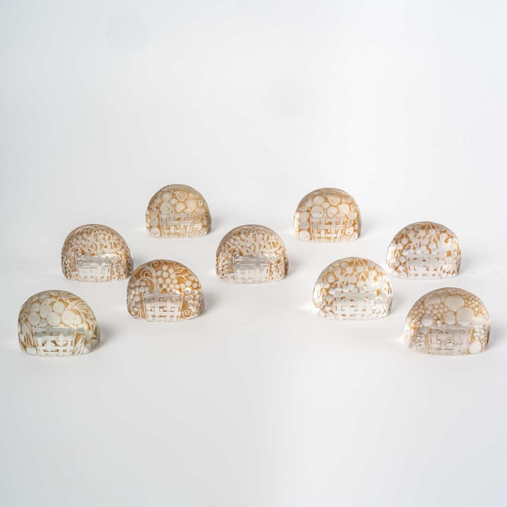 Suite de 9 Porte-Menus verre blanc patiné sépia de René LALIQUE | Biron Suite de 9 Porte-Menus verre blanc patiné sépia de René LALIQUE