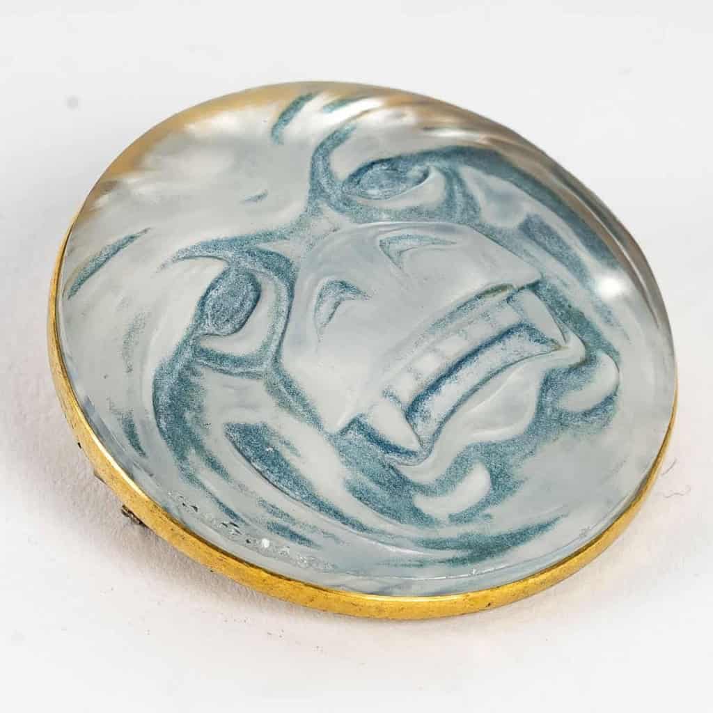Broche « Masque » verre blanc sur clinquant argent patiné bleu de René LALIQUE | Biron Broche "Masque" verre blanc sur clinquant argent patiné bleu de René LALIQUE