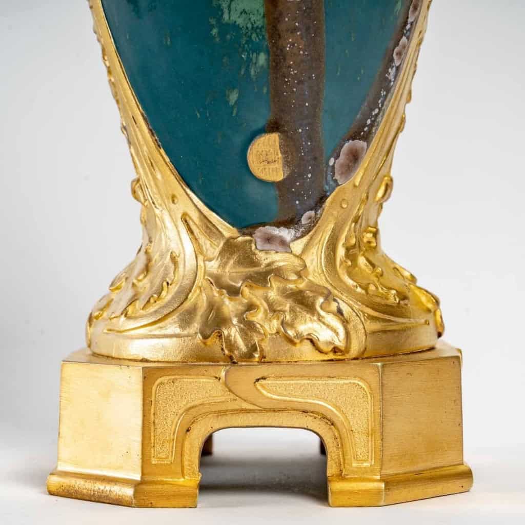 Vase en grès flammé à décor de coulures, sur socle en bronze à patine dorée, signé Paul Louchet, début XXe siècle. | Biron Vase en grès flammé à décor de coulures, sur socle en bronze à patine dorée, signé Paul Louchet, début XXe siècle.