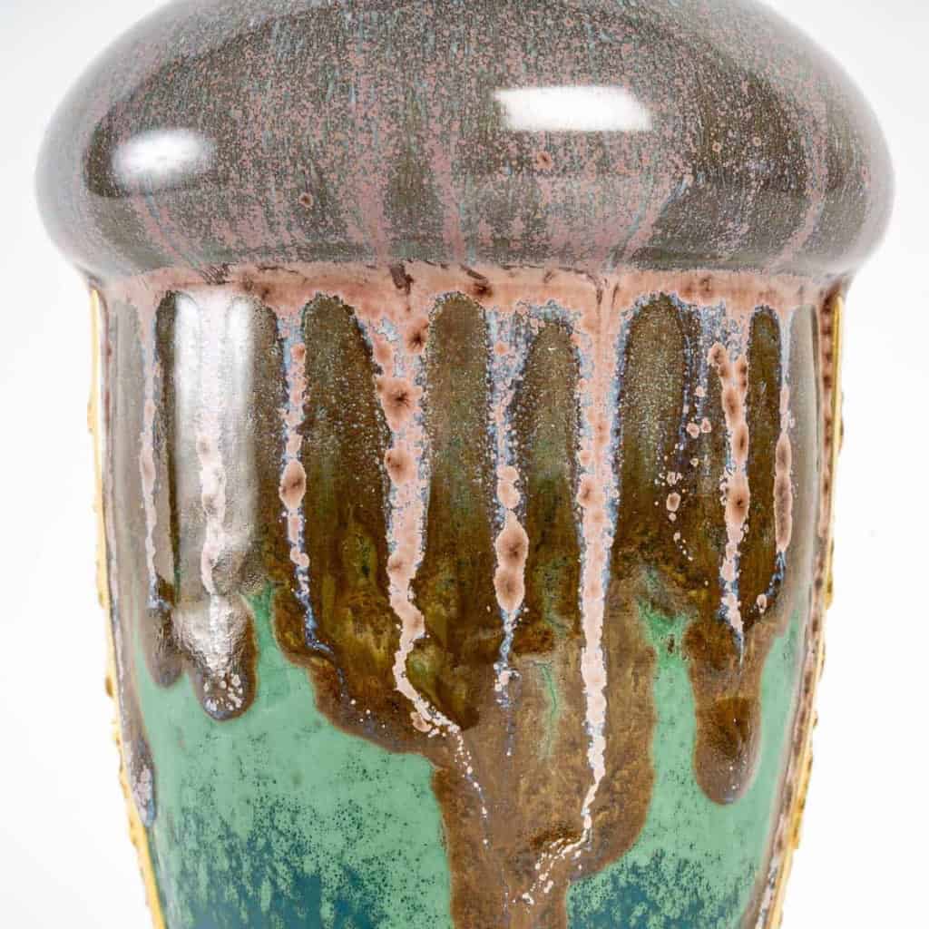 Vase en grès flammé à décor de coulures, sur socle en bronze à patine dorée, signé Paul Louchet, début XXe siècle. | Biron Vase en grès flammé à décor de coulures, sur socle en bronze à patine dorée, signé Paul Louchet, début XXe siècle.