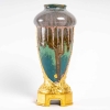 Vase en grès flammé à décor de coulures, sur socle en bronze à patine dorée, signé Paul Louchet, début XXe siècle. | Biron Vase en grès flammé à décor de coulures, sur socle en bronze à patine dorée, signé Paul Louchet, début XXe siècle.