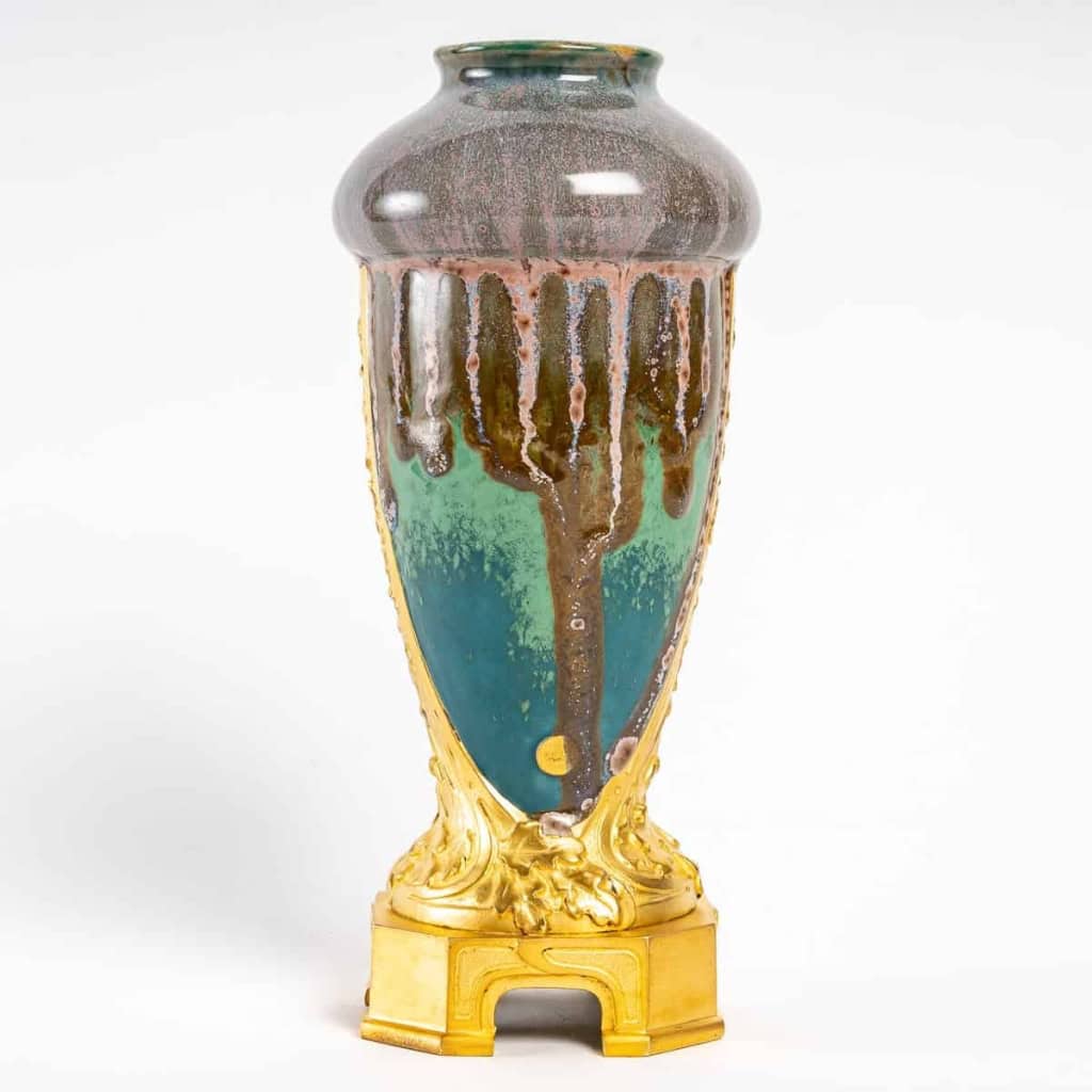 Vase en grès flammé à décor de coulures, sur socle en bronze à patine dorée, signé Paul Louchet, début XXe siècle. | Biron Vase en grès flammé à décor de coulures, sur socle en bronze à patine dorée, signé Paul Louchet, début XXe siècle.