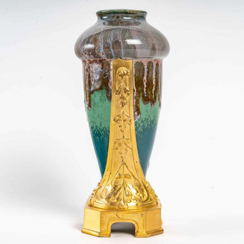 Vase en grès flammé à décor de coulures, sur socle en bronze à patine dorée, signé Paul Louchet, début XXe siècle. | Biron Vase en grès flammé à décor de coulures, sur socle en bronze à patine dorée, signé Paul Louchet, début XXe siècle.