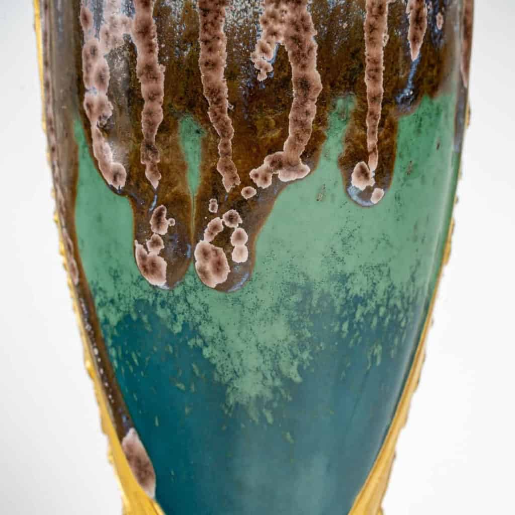 Vase en grès flammé à décor de coulures, sur socle en bronze à patine dorée, signé Paul Louchet, début XXe siècle. | Biron Vase en grès flammé à décor de coulures, sur socle en bronze à patine dorée, signé Paul Louchet, début XXe siècle.