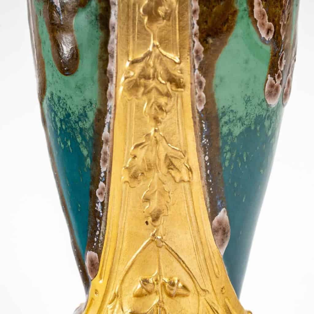 Vase en grès flammé à décor de coulures, sur socle en bronze à patine dorée, signé Paul Louchet, début XXe siècle. | Biron Vase en grès flammé à décor de coulures, sur socle en bronze à patine dorée, signé Paul Louchet, début XXe siècle.