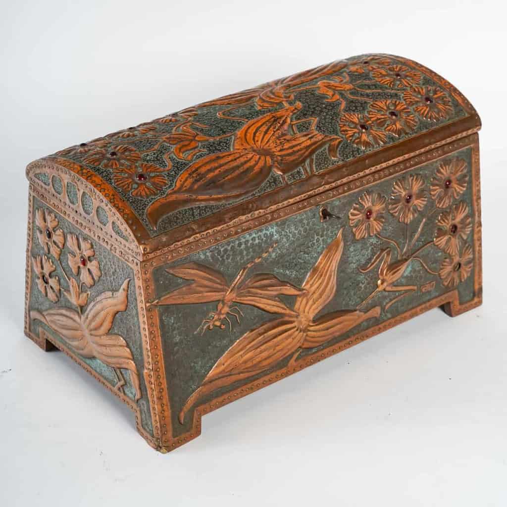 Coffret Art Nouveau en cuivre repoussé sur âme de bois, serti de cabochons de verre à décor de fleurs et libellule, signé « GIM », début du XXe siècle. | Biron |||||||||