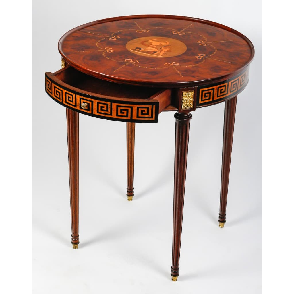 Table ronde ouvrant par un tiroir en marqueterie de bois précieux. Plateau finement marqueté d’une scène d’après l’Antique | Biron Table ronde ouvrant par un tiroir en marqueterie de bois précieux. Plateau finement marqueté d'une scène d'après l'Antique