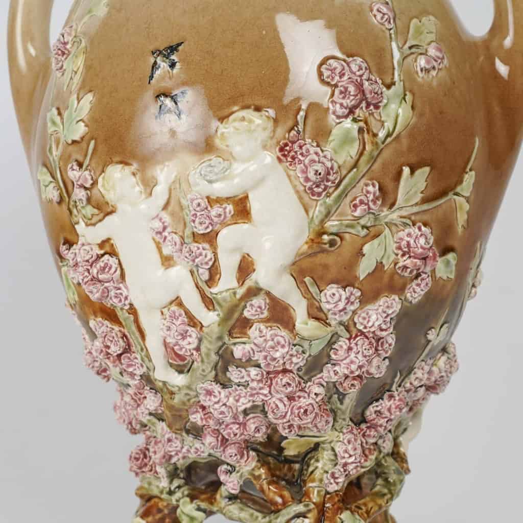 Vase en barbotine à décor en pâte sur pâte de putti et fleurs, signé Carrier-Belleuse pour la faïencerie de Choisy Le Roi, circa 1890 | Biron Vase en barbotine à décor en pâte sur pâte de putti et fleurs, signé Carrier-Belleuse pour la faïencerie de Choisy Le Roi, circa 1890