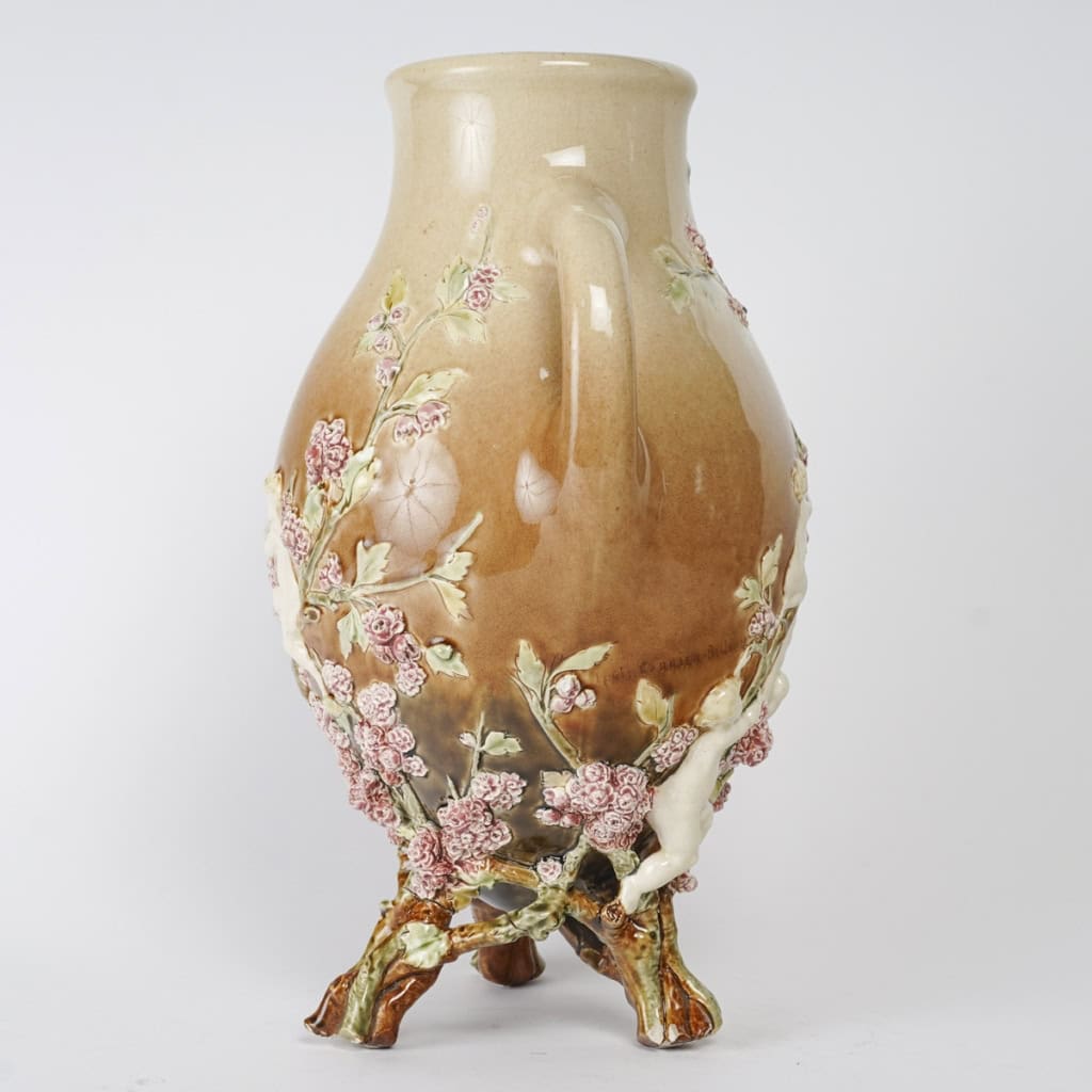 Vase en barbotine à décor en pâte sur pâte de putti et fleurs, signé Carrier-Belleuse pour la faïencerie de Choisy Le Roi, circa 1890 | Biron Vase en barbotine à décor en pâte sur pâte de putti et fleurs, signé Carrier-Belleuse pour la faïencerie de Choisy Le Roi, circa 1890