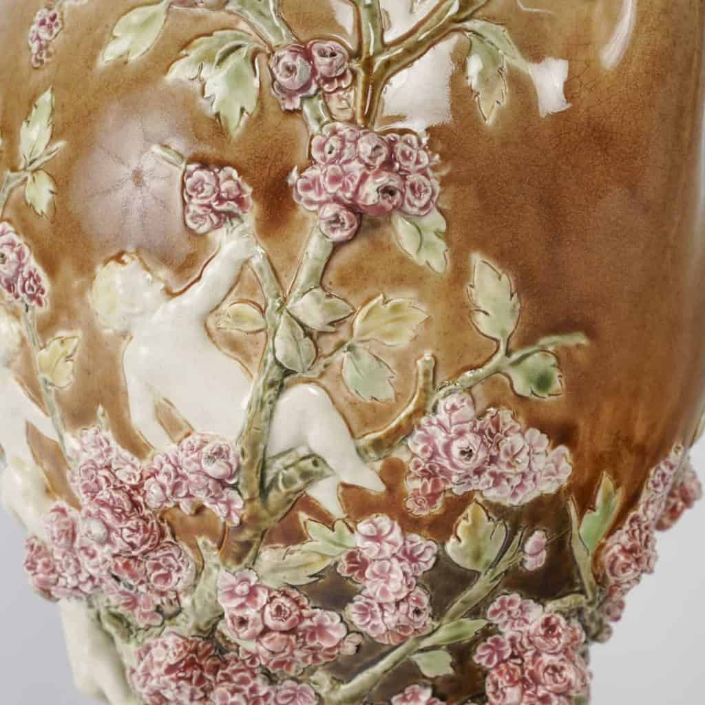 Vase en barbotine à décor en pâte sur pâte de putti et fleurs, signé Carrier-Belleuse pour la faïencerie de Choisy Le Roi, circa 1890 | Biron Vase en barbotine à décor en pâte sur pâte de putti et fleurs, signé Carrier-Belleuse pour la faïencerie de Choisy Le Roi, circa 1890