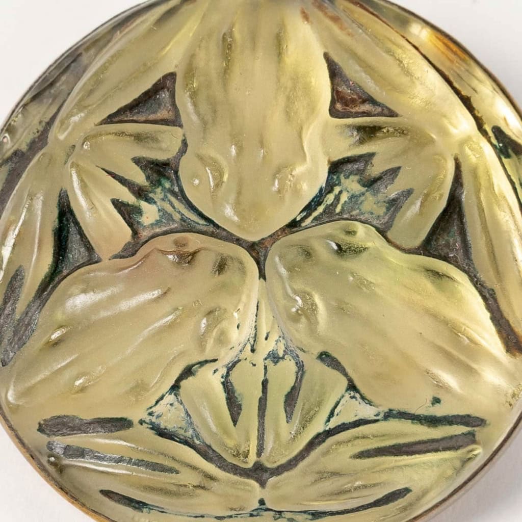 Broche « Grenouilles » verre blanc patiné vert foncé sur clinquant jaune de René LALIQUE | Biron Broche "Grenouilles" verre blanc patiné vert foncé sur clinquant jaune de René LALIQUE