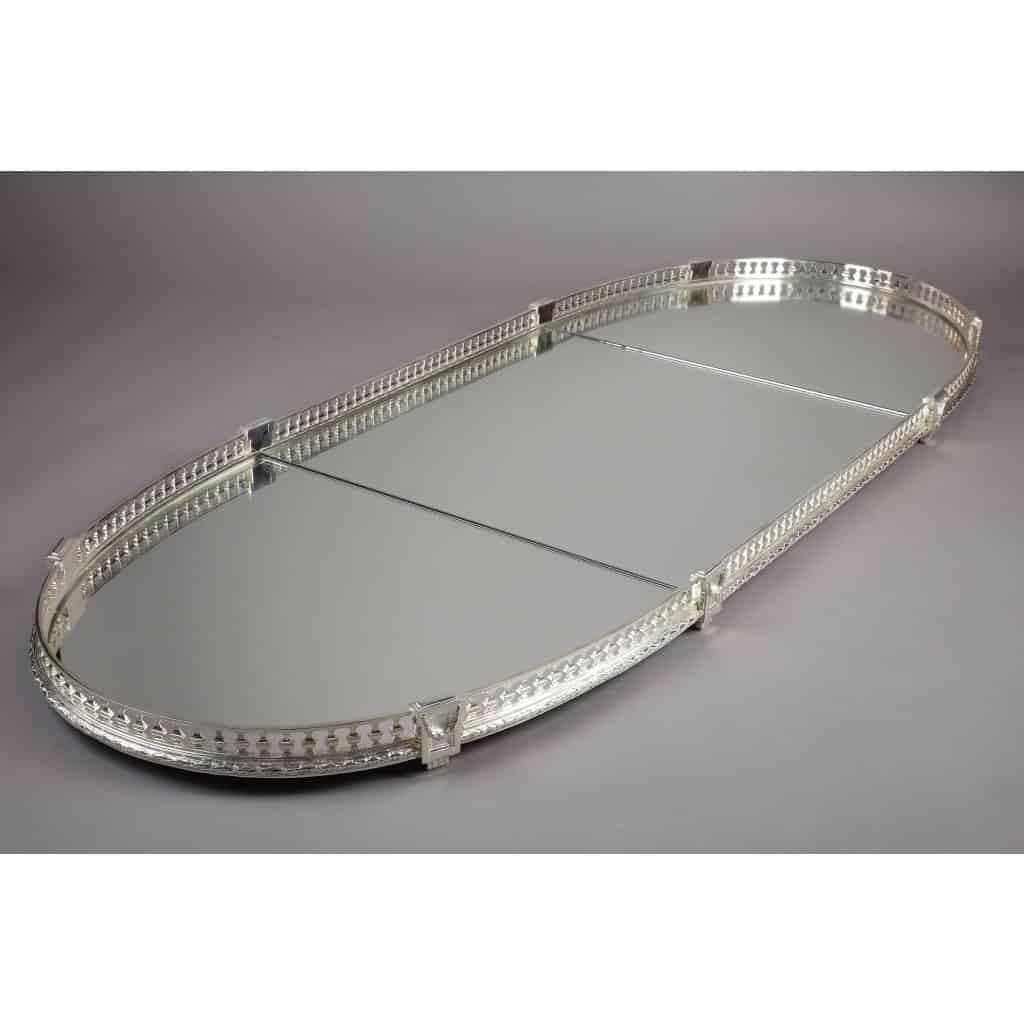 Surtout de table miroir en 3 parties fin XIXe – attribué à A. Aucoc | Biron A. AUCOC - Surtout de table en 3 parties ovale circa fin XIXe SURTOUT DE TABLE en trois parties de forme ovale, à fond de miroirs, ceinturé par une grille en bronze ponctuée de chapiteaux formant les pieds. Finition feuille de laurier. Les miroirs ont été changés et les fonds sont recouverts de tissu bleu. Dimensions : longueur 145 cm – largeur 55 cm – hauteur 6 cm Matières : bronze, miroirs Epoque : fin XIXe Orfèvre : attribué à A. AUCOC