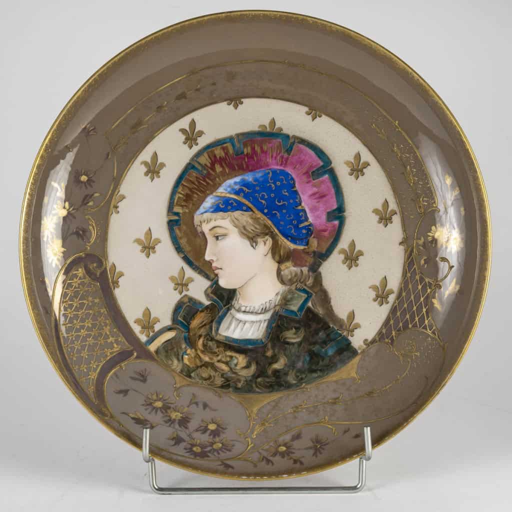 Superbe plat en porcelaine, signé Tressemanes & Vogt, polychrome émaillé figurant une jeune femme de profil dans le médaillon central, Travail français de la fin du XIXe siècle, circa 1882-1907. | Biron 