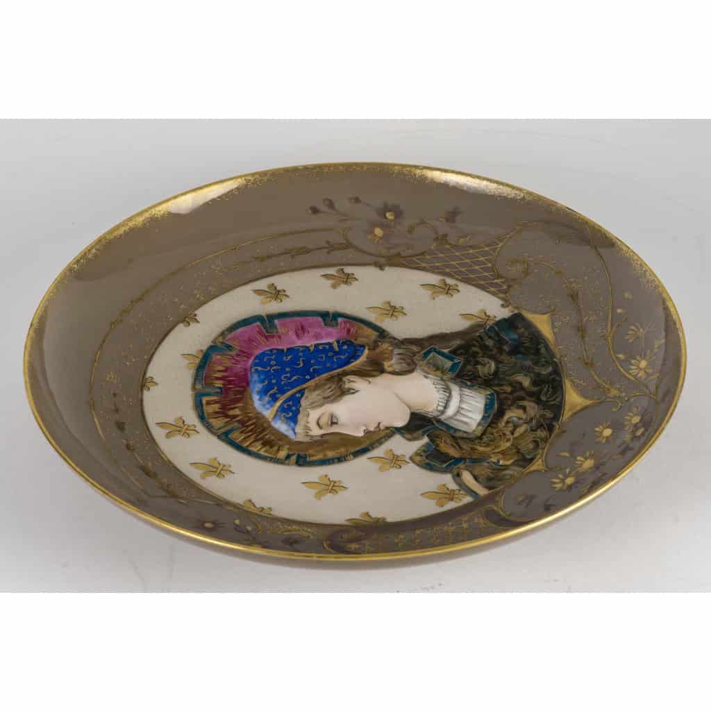 Superbe plat en porcelaine, signé Tressemanes & Vogt, polychrome émaillé figurant une jeune femme de profil dans le médaillon central, Travail français de la fin du XIXe siècle, circa 1882-1907. | Biron 
