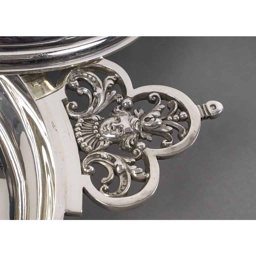 Orfèvre Cardeilhac – Garniture de Table « Renaissance » Mascaron Argent Fin XIXè | Biron CARDEILHAC - Garniture de table "Renaissance" Mascaron Argent fin XIXè Garniture de table en argent massif Modèle Renaissance aux mascarons de la fin du XIXè siècle, composée des cinq pièces suivantes : Un Légumier couvert Modèle N°1 en argent massif 1er titre, de forme ronde à décor de fleur de lys et de fer de lance en applique, dans le goût de la Renaissance. Le couvercle à doucine bombée est surmonté d'une terrasse en applique ciselée et d'un frételet ajouré. De chaque côté du légumier les anses à oreilles sont repercées et ornées d'un mascaron. - Dimensions : longueur aux anses 34,5 cm - Diamètre 20,5 cm -hauteur 13,5 cm environ. Poids : 1136 grammes Un Légumier couvert Modèle N°2 en argent massif de forme circulaire, modèle « Renaissance » à décor de fer de lances en applique sur le corps et sur la terrasse du couvercle dont la prise est en forme de bouton monogrammé. Les anses trilobées, flanquées de chaque côté, sont repercées de fleurs de lys et d’un mascaron. Dimensions : longueur aux anses 32 cm – diamètre au col 20 cm - Hauteur 12,5 cm - Poids : 1 240 grammes Un Plat rectangulaire octogonale en argent massif modèle " Fer de lance" avec une tête de mascaron et décor de fer de lance. Dimensions longueur 42 cm - largeur 28 cm - Poids : 1200 grammes Un Plat rectangulaire octogonale en argent massif à décor de fer de lance et de deux têtes de mascarons - Dimensions : longueur 45 cm largeur 30 cm - Poids : 1350 grammes Une Saucière en argent massif, de forme ovale, flanquée de deux anses latérales repercées et ornées d’un mascaron, sur plateau adhérent octogonale à décor de fer de lance. Doublure intérieure en argent - .Dimensions : longueur aux anses : 24 cm – largeur 11,5 cm- Poids : 910 grammes Poinçon MINERVE – Orfèvre CARDEILHAC Armand Edouard(1885/1904) – Origine France/Paris