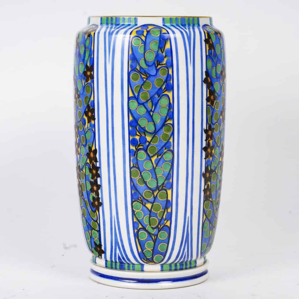 Très élégant vase en porcelaine blanche à décor abstrait végétalisant géométriques dans les tons de bleu, vert, noir, jaune et rouge. Pièce signée, au cachet de la Manufacture National de Sèvres, décor peint d’après l’artiste Jane Levy, travail de 1925. | Biron 