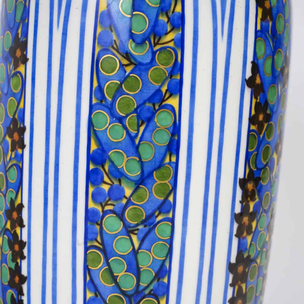 Très élégant vase en porcelaine blanche à décor abstrait végétalisant géométriques dans les tons de bleu, vert, noir, jaune et rouge. Pièce signée, au cachet de la Manufacture National de Sèvres, décor peint d’après l’artiste Jane Levy, travail de 1925. | Biron 