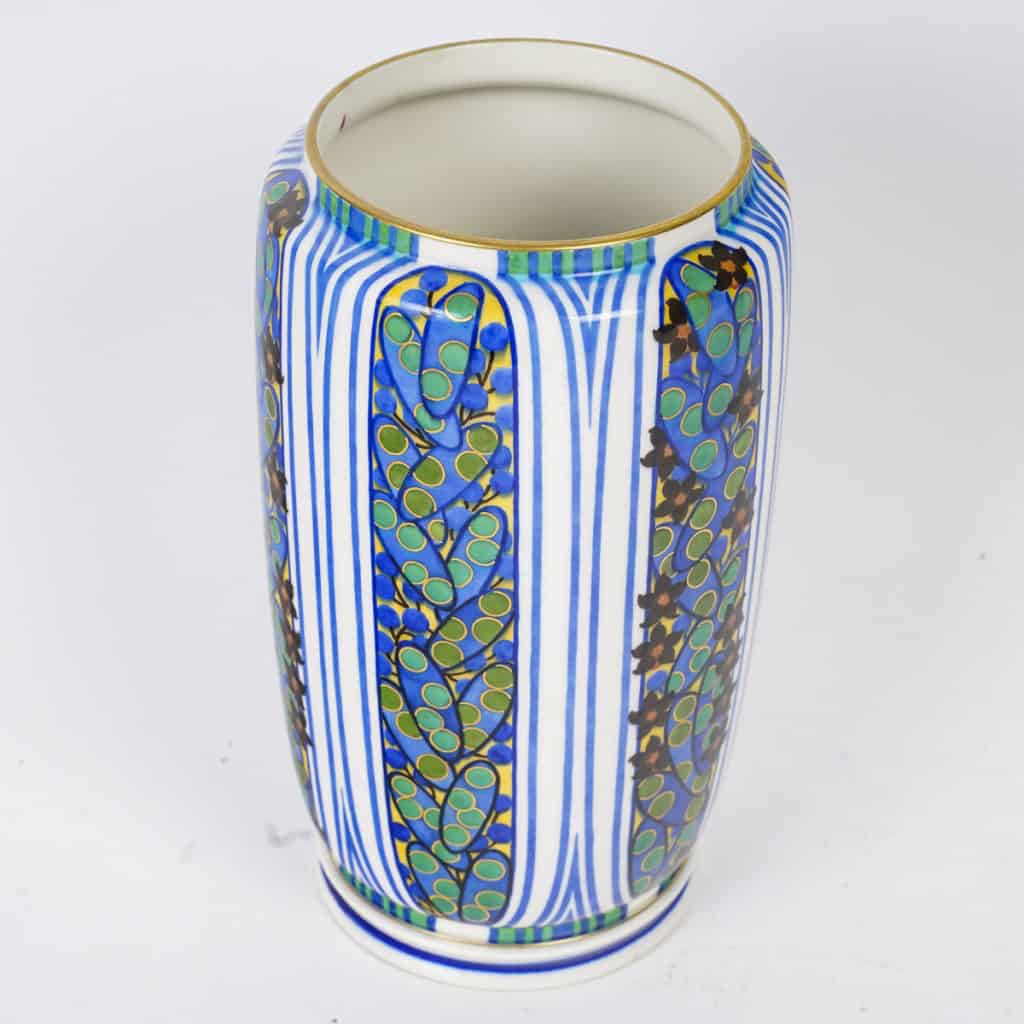 Très élégant vase en porcelaine blanche à décor abstrait végétalisant géométriques dans les tons de bleu, vert, noir, jaune et rouge. Pièce signée, au cachet de la Manufacture National de Sèvres, décor peint d’après l’artiste Jane Levy, travail de 1925. | Biron 