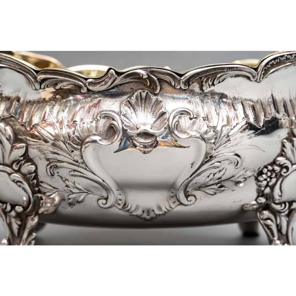 J.B. Francois – Importante Jardinière en argent massif XIXe | Biron Orfèvre J.B. FRANCOIS - Importante Jardinière en argent massif XIXe Jardinière en argent de forme oblongue, reposant sur quatre pieds griffes en crosse feuillagée. Le corps est orné au repoussé d’une frise de rainures. Sur les grands côtés se trouve un cartouche rocaille surmonté d’une coquille. Les anses solidaires sont à motif d’enroulement. La doublure intérieure amovible est en cuivre repoli. Dimensions : longueur 53 cm –Largeur 28,5 cm – hauteur 23,5 cm Matière : Argent 1er titre 950/°°° Poids : 3 kg Poinçon / MINERVE Epoque : XIXe vers 1880 Orfèvre : J.B. FRANCOIS Origine : France/Paris