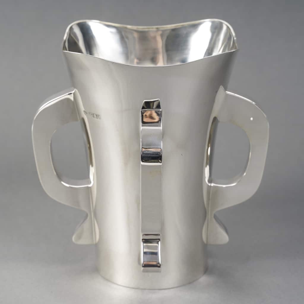 Orfèvre G & S. Ltd – VASE MODERNiSTE EN ARGENT MASSIF LONDRES 1916 | Biron Orfèvre G & S. Ltd - VASE MODERNiSTE EN ARGENT MASSIF LONDRES 1916 Exceptionnel Vase moderniste en argent massif base ronde légèrement évasé vers le col, corps uni flanqué de quatre anses de style transition entre l’art nouveau et l’art déco. Pièce très originale exécutée au début du XXe siècle. Très bon état. Dimensions : hauteur 20,5 cm – diamètre base 9,9 cm – diamètre col 17 cm Matière : Argent 1er titre 925/1°°° Poids : 854 grammes Poinçon : ARGENT LONDRES 1916 Epoque : EDOUARD VII Orfèvre : Goldsmiths' & Silversmiths' Company Ltd Origine : LONDRES/GRANDE BRETAGNE Biographie : Cette grande entreprise de bijouterie et d'orfèvrerie de détail a été fondée en 1880 au 112 Regent Street. Les associés d'origine étaient William Gibson et John Lawrence Langman. Après l'absorption en 1893 de la Goldsmiths' Alliance Ltd, la Goldsmiths & Silversmiths Co a été transformée en société à responsabilité limitée. En 1952, la société a fusionné avec Garrard & Co. Bibliographie : John Culme, « Le répertoire des orfèvres et des argentiers 1838-1914 », Woodbridge 1987