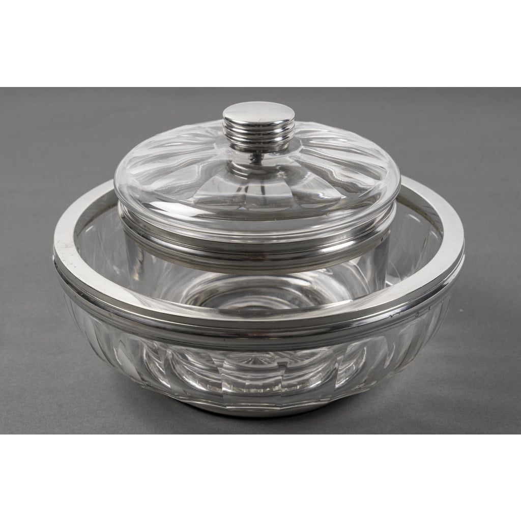 BACCARAT – BOL A CAVIAR EN CRISTAL TAILLE DEUX PIECES XXè ART DECO | Biron BACCARAT - BOL A CAVIAR EN CRISTAL TAILLE DEUX PIECES XXè ART DECO BOL A CAVIAR en cristal de BACCARAT, taillé de larges languettes et monté sur une batte ronde cerclée d’argent massif sur fond étoilé. Sur ce fond vient s’encastrer un pot en cristal uni cerclé d’argent au col, avec un couvercle taillé de languettes plates, surmonté d’une prise cylindrique en argent .Dimensions : BOL : Diamètre au col 25,5 cm – Diamètre base 14,5 cm – hauteur 10 cm POT : diamètre au col 17 cm – Diamètre base 10,5 cm - hauteur 15 cm Matières : CRISTAL & ARGENT Poinçon : MINERVE Poids brut : 3 845 Grammes Epoque : ART DECORATIF vers 1930 Provenance : CRISTALLERIES DE BACCARAT Origine : France/Paris