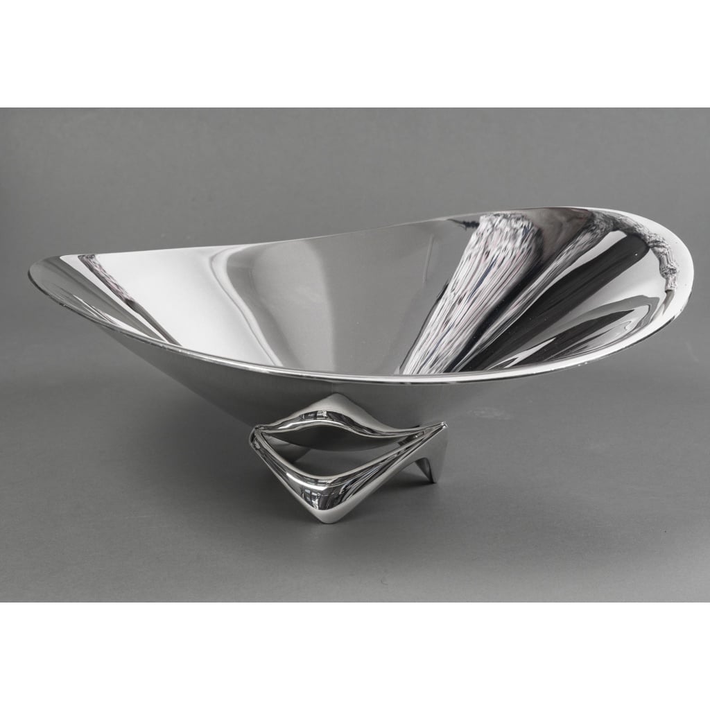 Orfèvre G. Jensen – Designer H. Koppel – Centre de table en argent massif XXe | Biron G. Jensen - H. Koppel - Centre de table en argent massif XXe Centre de table en argent massif représenté par une grande coupe hélicoïdale (en forme d’hélice) Modèle “980 A” conçue en 1948 par le designer HENNING KOPPEL (1918 - 1981) pour l’Orfèvre G. JENSEN Dimensions : La plus grande hauteur : 16 cm -La plus grande largeur 40 cm Matière : Argent 925/°°° Poids : 3703 Grammes Poinçon : HK - 925 S - B11 - GEORG JENSEN Epoque : XXè Orfèvre : GEORG JENSEN Le designer danois Henning Koppel (Copenhague 1918-1981) a d'abord étudié le dessin, puis la sculpture avec Anker Hoffmann à l'Académie royale des arts danoise à Copenhague. Il a commencé à créer de l'or et de l'argent en exil en Suède pendant la Seconde Guerre mondiale chez Orrefors et Svenskt Tenn. Il est retourné à Copenhague en 1945 et a travaillé avec l'orfèvre Georg Jensen jusqu'à sa mort en 1981. Ses créations, appelées "New Look", avaient une conception créative totalement nouvelle. S'éloignant des éléments décoratifs de l'Art nouveau et de la géométrie de l'époque Art déco, ses travaux présentent des surfaces sobres avec une forme de base légèrement asymétrique et d'apparence organique. Ses travaux ont été récompensés par des médailles d'or à la Triennale de Milan en 1951, 1954 et 1957. Lit. Janet Drucker, Georg Jensen - A Tradition of Splendid Silver, 1997, p. 252