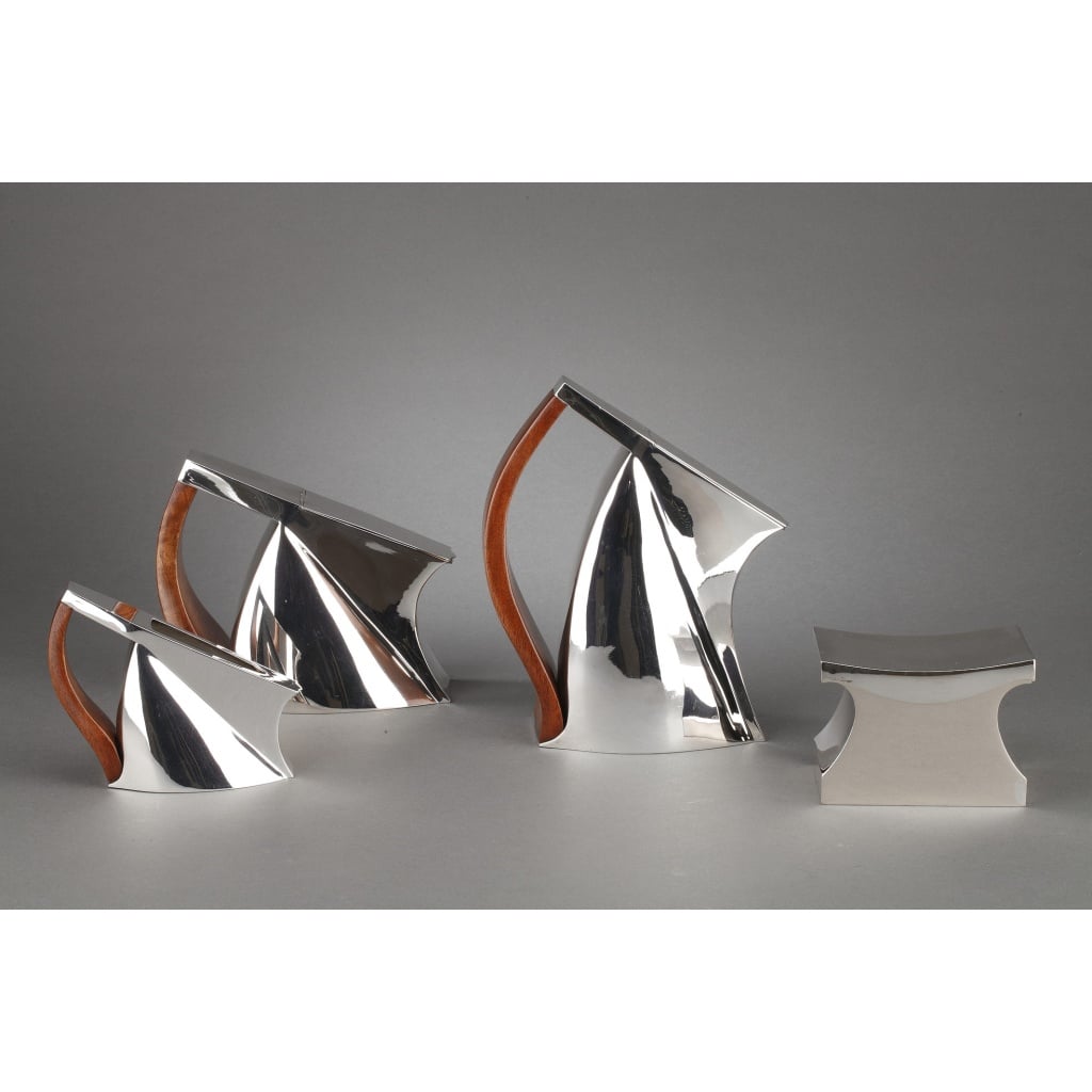 Rare et exceptionnel Pierre CARDIN - Service thé café 4 pièces argent massif modèle futuriste XXè service à thé café 4 pièces en argent massif de type futuriste composé d'une théière, d'une cafetière, d'un pot à lait, d'un sucrier couvert, les anses sont en bois teinté palissandre, chaque pièce est marquée G.SILVA sous la base. TRAVAIL FAIT A LA MAIN . Pierre CARDIN (1922-2020) designer/Editeur & Giuseppe SILVA orfèvre à Milan, ont conçu vers 1975 le modèle "ROBY" qui a remporté le 1er prix de la Vème édition du Premio Nazionale Sant'Eligio Arte Orafa en 1975. Dimensions : cafetière ht 23 cm - Théière ht 16 cm - sucrier ht 9 cm - pot à lait ht 12 cm Matière : argent massif Poids : 2820 grammes Poinçon : 84 MI-(Milan) Epoque : XXè 1970/1975 Orfèvre : Giuseppe SILVA Origine : ITALIE DU NORD