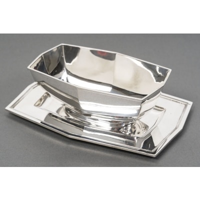 CARDEILHAC – Saucière sur plateau en argent massif ARTDECO vers 1930 Très belle saucière en argent massif sur piédouche, vissée sur son présentoir adhérent de forme hexagonale, léger liseré au contour du plateau. Dimensions : Longueur 22 cm largeur 15 cm Matière : Argent 1er titre 950/°°° Poids : 586 grammes Poinçon : MINERVE Epoque : ART DECO Orfèvre : CARDEILHAC à PARIS Origine : FRANCE/Paris