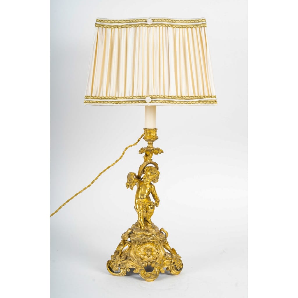 Paire de bougeoirs d’époque Napoléon III à décor de Putti en bronze doré, montée en lampes | Biron 