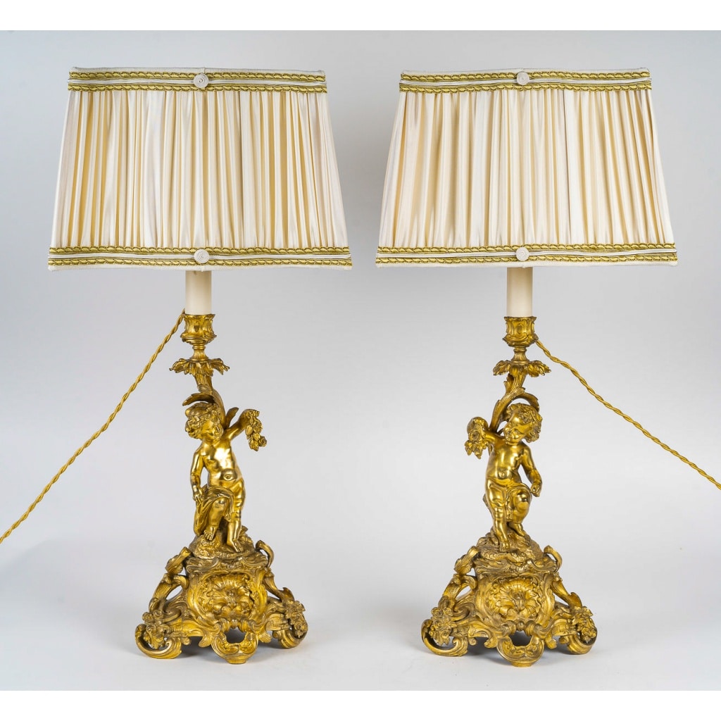 Paire de bougeoirs d’époque Napoléon III à décor de Putti en bronze doré, montée en lampes | Biron 