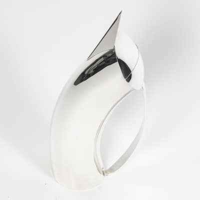 CLETO MUNARI – Pichet en argent moderniste – Italie du NORD Pichet en argent massif de forme cylindrique courbé, avec bec verseur pointu et large anse en ruban, couvercle à charnière. La forme est géométrique, ligne pure à structure moderne. Cette pièce porte le N° 28 sur une édition limitée 249. Datée 2003 Le Designer de cette pièce est DALISI RICARDO ( 1931/2022) Dimensions : hauteur 32 cm au bec – Hauteur 14 cm à l’anse Matière : Argent 1er titre 925/°°° Poids : 730 grammes Poinçon : Titre 925/°°° - et ville 1702 VI N° du modèle O28/249/03 Epoque : XXè Orfèvre : CLETO MUNARI Origine : VICENZA – ITALIE du NORD
