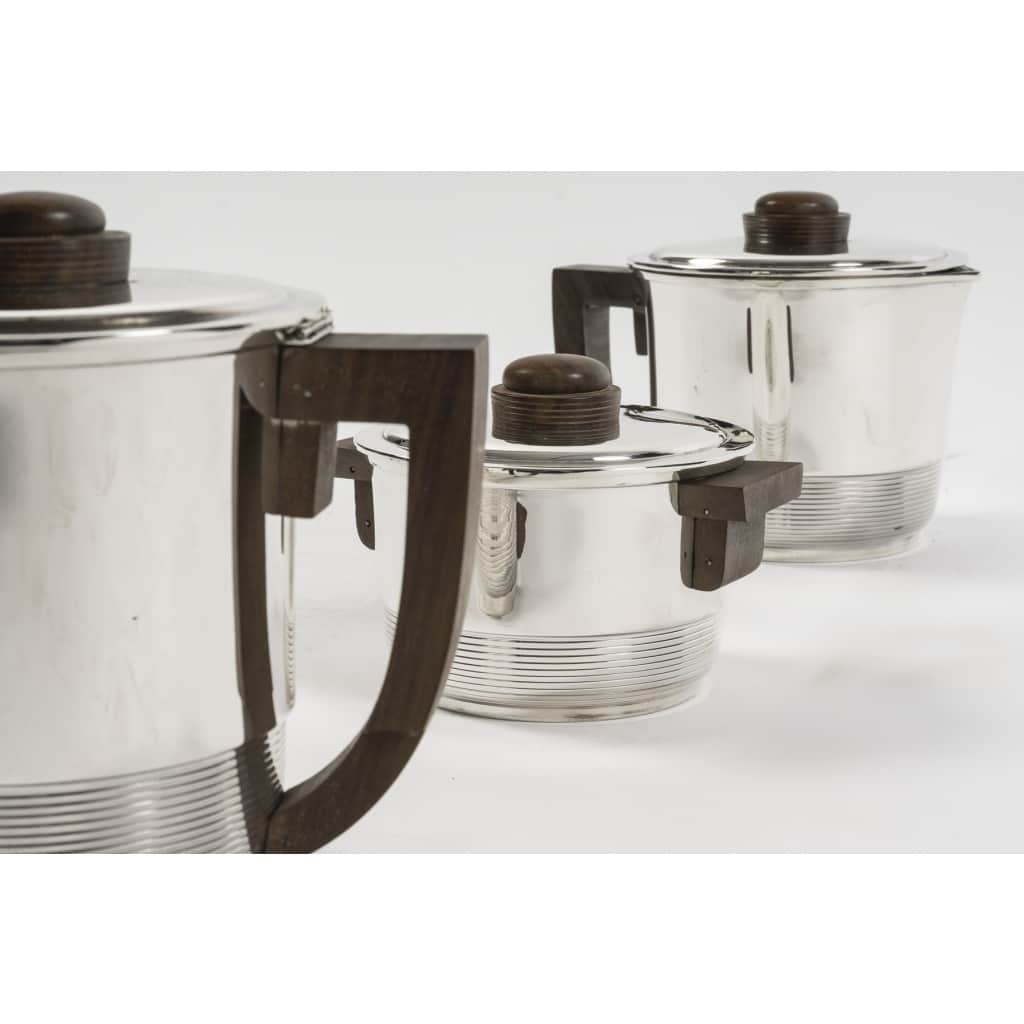 Fouquet Lapar – Service thé café 3 pièces argent massif ART DECO | Biron Fouquet Lapar - Service thé café 3 pièces argent massif ART DECO Service en argent massif, composé d’une Théière, d’une cafetière, et d’un sucrier couvert intérieur en vermeil, de forme cylindrique à décor fileté, couvercle à charnière pour les pots à thé et café. Les anses et prises sont en palissandre. Dimensions : Théière : Longueur : 18cm, hauteur : 14 cm Diamètre base : 10cm - Poids brut : 534 grs Cafetière : Longueur : 17cm hauteur : 16,5 cm Diamètre base 8,5 cm - Poids brut : 556 grs Sucrier : Longueur : 14,5 cm, hauteur : 9,5 cm Diamètre base : 9,5 cm - Poids brut : 364 grs Poids total brut : 1 Kg 454 Matière : argent 1er titre 950/°°° Poinçon : MINERVE Epoque : ART DECO vers 1937 Orfèvre : FOUQUET LAPAR Origine : France/Paris