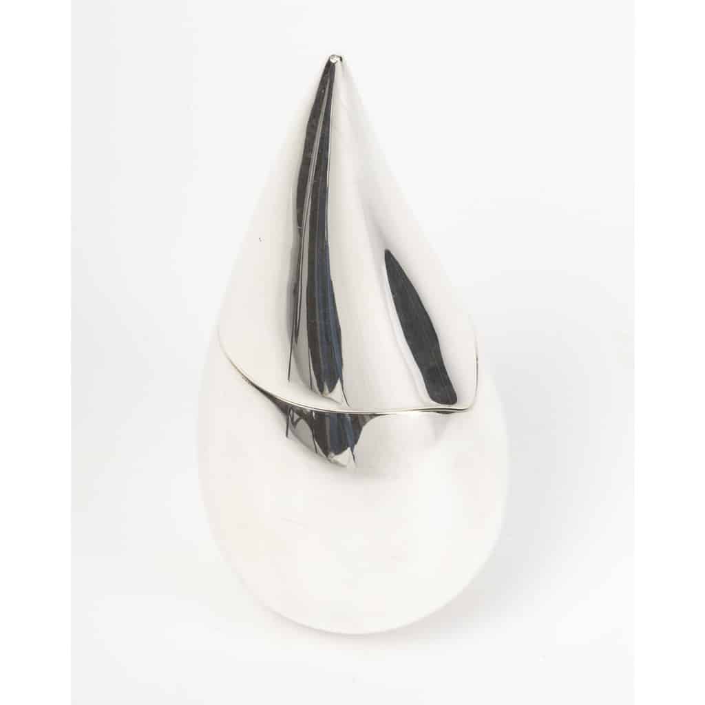 CHRISTOFLE – boîte en argent massif moderniste XXIe siècle | Biron Cette pièce en argent CHRISTOFLE – boite en argent massif moderniste XXIe siècle massif adopte une forme moderne et épurée de GOUTTE D’EAU STYLISEE. Sa silhouette lisse, élancée et symétrique est marquée par un point culminant très fin lui conférant une élégance sculpturale. Cette pièce contemporaine allie pureté des lignes et raffinement du matériau, illustrant l’esprit novateur de la maison CHRISTOFLE au XXIe siècle. Cette pièce éditée à 1000 exemplaire porte le N°779. Cet objet est une véritable sculpture. Dimensions : hauteur 20 cm - Envergure maxi : 10 cm Diamètre base : 4 cm Matière : argent 1er titre 950/°°° Poids : 422 grammes Poinçon : MINERVE Epoque : XXIe siècle Orfèvre : CHRISTOFLE Origine : France/Paris