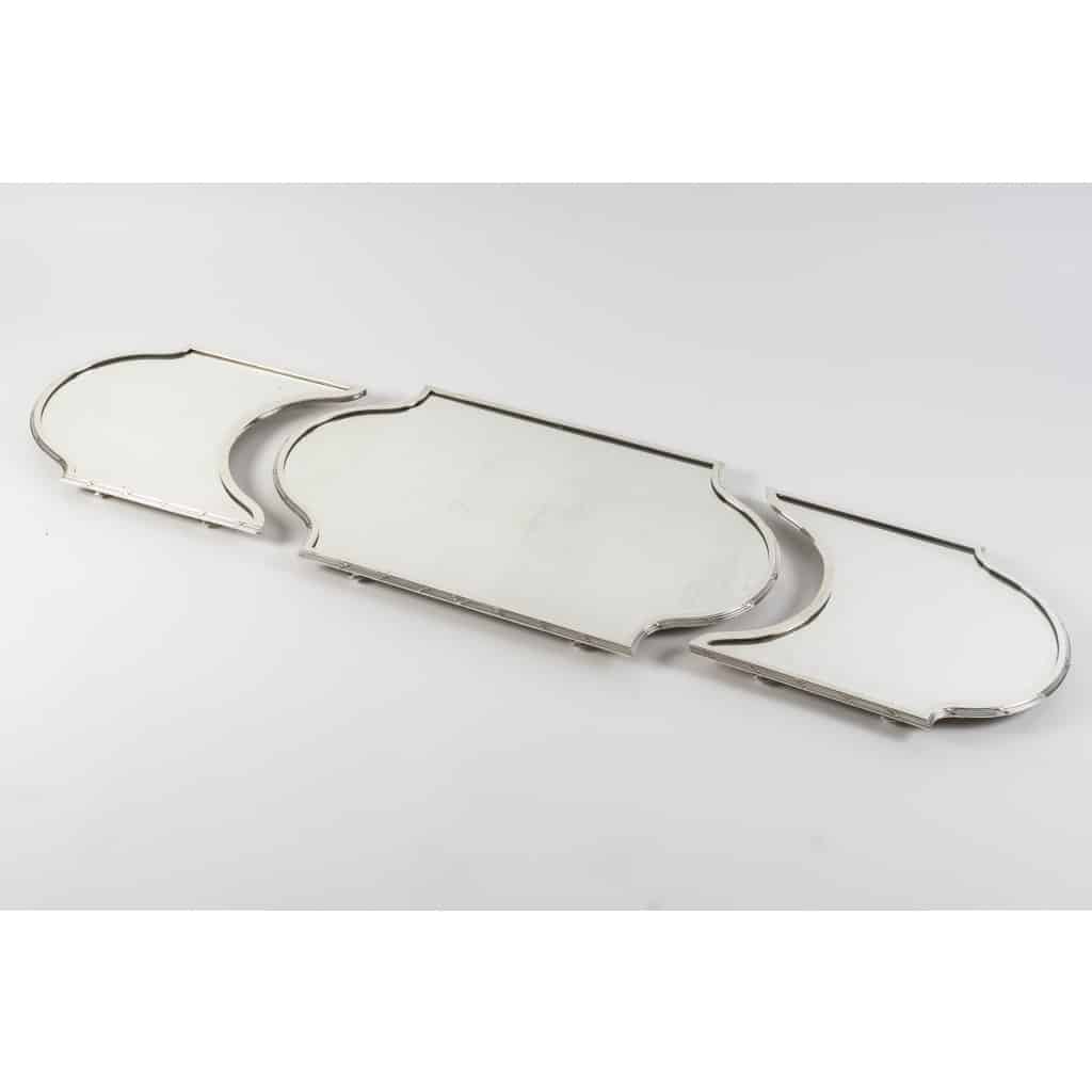 Orfèvre QUEILLE – Surtout de table en argent massif 3 parties NAPOLEON III, XIXe | Biron Orfèvre QUEILLE - Surtout de table en argent massif 3 parties XIXe NAPOLEON III Important surtout de table en trois parties de style Louis XVI, à fond de miroirs, sur un parquet de bois, serti d'une forte lingotière en argent massif à filets et rubans croisés, monté sur des pieds toupies. Dimensions : longueur totale 139 cm Milieu : 74 cm x 42 cm x 4 cm 1/2 cotés : 42 cm x 35,5 cm Matière : argent 1er titre 950/°°° Poinçon : MINERVE Epoque : XIXè NAPOLEON III Orfèvre : QUEILLE à PARIS Origine : France/Paris