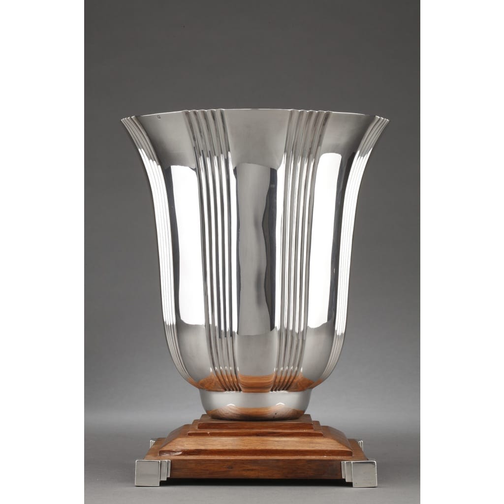 LAPPARRA - Vase en argent massif époque ART DECO Grand vase en argent massif de forme balustre décoré de rainures verticales, fixé sur un socle en bois à dégrés serti d'argent au quatre coins . Dimensions : hauteur : 27,5 cm - diamètre 21,5 cm - base 17,5 cm Matière : argent 1er titre 950/°°° Poids brut : 2.475 grammes brut Poinçon : Minerve Epoque : ART DECO Orfèvre : LAPPARRA à PARIS Origine : FRANCE