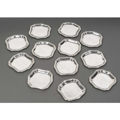 Bloch Eschwege - 12 plats en argent massif , Louis XV début XXe Suite de douze plats en argent massif de style LOUIS XV, de forme chantournée, ceinturée de filets. Très bon état, petites rayures d'usage. Dimensions : 15 cm x 14,5 cm – Hauteur 1 cm Matière : Argent 1er titre 950/1°°° Poinçon : MINERVE Poids total : 2 Kg 380 Epoque : début XXe Orfèvre : BLOCH - ESCHWEGE Origine : France/Paris