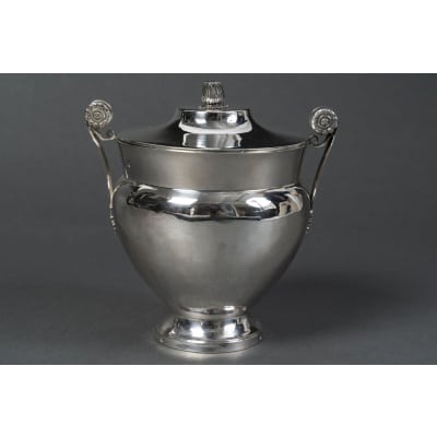 JBC ODIOT – Sucrier couvert en argent époque 1er empire 1809/1818 Élégant sucrier couvert de forme ovoïde en argent massif, reposant sur un piédouche circulaire, avec couvercle bombé orné d’une prise stylisée en graine. Les anses latérales, finement ciselées de palmettes et de rosaces sur fond amati, témoignent d’un répertoire décoratif typique du goût néo-pompéien sous l’Empire. Pièce éxécutée entièrement au marteau. Le poinçon de garantie au 2e coq atteste d’une fabrication entre 1809 et 1818. Cette œuvre est signée Jean-Baptiste Claude Odiot, l’un des plus prestigieux orfèvres parisiens du Premier Empire, célèbre fournisseur de la Cour impériale et de nombreuses cours européennes. Il succède à son père et fait rayonner l’orfèvrerie française à travers des créations alliant rigueur architecturale et richesse ornementale, souvent inspirées de l’Antiquité. Dimensions : H. 14 cm – L. avec anses : 13,5 cm – Diam. base : 6 cm Matière : Argent 1er titre 950/1°°° Poids : 370 grammes Poinçons : SUR LA BASE 2eme COQ 1809/1818 PARIS– Récence du 2eme Coq – Poinçon du vieillard 1818/1838 avec recense du sanglier. SUR LE CORPS : 2eme COQ 1809/1818 PARIS– Récence du 2eme Coq – Poinçon du vieillard 1818/1838 avec recense du sanglier. SUR LE COUVERCLE : 2eme COQ 1809/1818 PARIS– Récence du 2eme Coq – Poinçon du vieillard 1818/1838 avec recense de la garantie SUR LE CORPS ET LE COUVERCLE : Poinçon en losange de JEAN BAPTISTE CLAUDE ODIOT Orfèvre : Jean-Baptiste Claude Odiot (Paris, 1763–1850) Origine : France/Paris