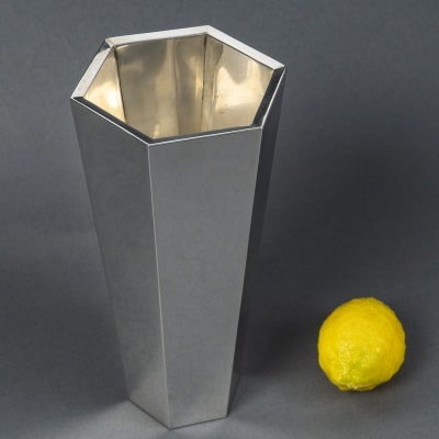TIFFANY & Co -Vase moderniste en argent à pans coupés XX Vase de forme hexagonale à pans coupés, aux parois légèrement évasées. Intérieur doré au vermeil. Ce modèle, d’une rigueur géométrique remarquable, est issu d’un dessin de Frank Lloyd Wright réalisé vers 1918 pour l’Hôtel impérial de Tokyo. Jamais produit à l’époque, ce vase fut réédité en 1985 par Tiffany & Co., grâce aux techniques modernes telles que le moulage par injection et le polissage acide, qui ont permis de rendre possible cette réalisation sophistiquée. Dimensions : Hauteur : 25,5 cm– Diamètre du col : 12,5 cm – Diamètre de la base : 7,5 cm Matériau : Argent massif, intérieur vermeil 925/1°°° Poinçon : Sterling FLORENCE Italie DU NORD - 175 FI Poids : 1 Kg 245 Attribué à Frank Lloyd Wright Edition : Tiffany & Co. Italie, vers 1985 Réédition autorisée par la Frank Lloyd Wright Foundation
