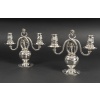 Georg JENSEN Paire de candélabres en argent massif, XXe ART DECO Superbe paire de candélabres à deux bras de lumière signée Georg Jensen, l’un des plus grands orfèvres du XXe siècle. Réalisés en argent massif (sterling silver), ces candélabres présentent un élégant piétement sphérique soutenant deux bras sinueux, ornés de binets évasés décorés d’un motif de baies en relief. La volute sommitale, typique du style naturaliste de Jensen, apporte équilibre et raffinement à l’ensemble. Dimensions : Hauteur 22 cm - largeur 25 cm Poids : 2 Kg 285 Epoque : Début XXè Orfèvre : Georg Jensen Poinçons : Georg Jensen – Denmark – Sterling - 324 État : excellent, argent légèrement poli, poinçons bien visibles. Ces pièces emblématiques du design scandinave début XXe siècle allient pureté des lignes, qualité artisanale et inspiration organique, caractéristiques des créations de Georg Jensen. Bibliographie : – Janet Drucker, Georg Jensen : A Tradition of Splendid Silver, New York, 1997, modèles similaires reproduits. Candélabre N°324 conçu par GEORG JENSEN 1919. Avec l'aimable autorisation de Georg Jensen/Royal Copenhagen. Un exemple similaire se trouve dans les collections du METROPOLITAIN MUSEUM OF ART NEW YORK Ces candélabres illustrent parfaitement l’esthétique organique du maître orfèvre Georg Jensen (1866-1935), inspirée par la nature et caractéristique du style Arts & Crafts scandinave.